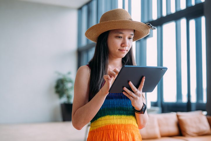 Young lady in a colourful dress investigating customized insurance plans from her tablet.